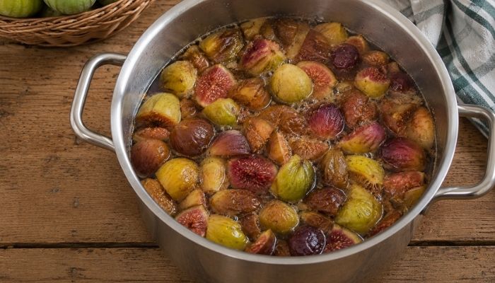 Fichi maturi tagliati a pezzi in una pentola capiente e coperti di acqua per preparare il vincotto di fichi